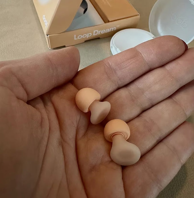 Person holding Loop Dream peach earplugs in palm of their hand