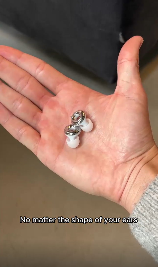 A close-up of a person's open palm holding a pair of Loop Switch 2 Silver, with text at the bottom reading 'No matter the shape of your ears.'.