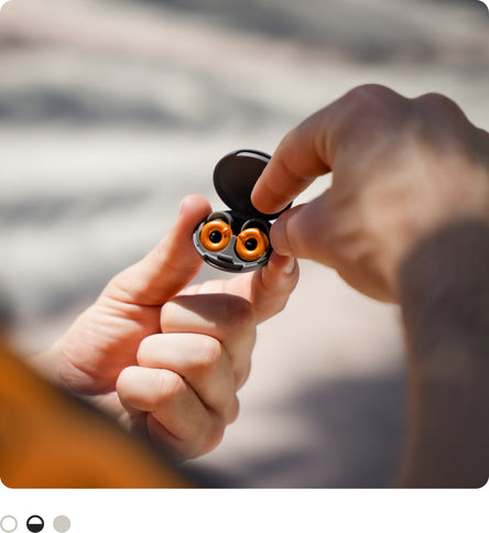 A close-up of a person holding an open McLaren x Loop Switch 2 case with two photographed outdoors against a blurred background.